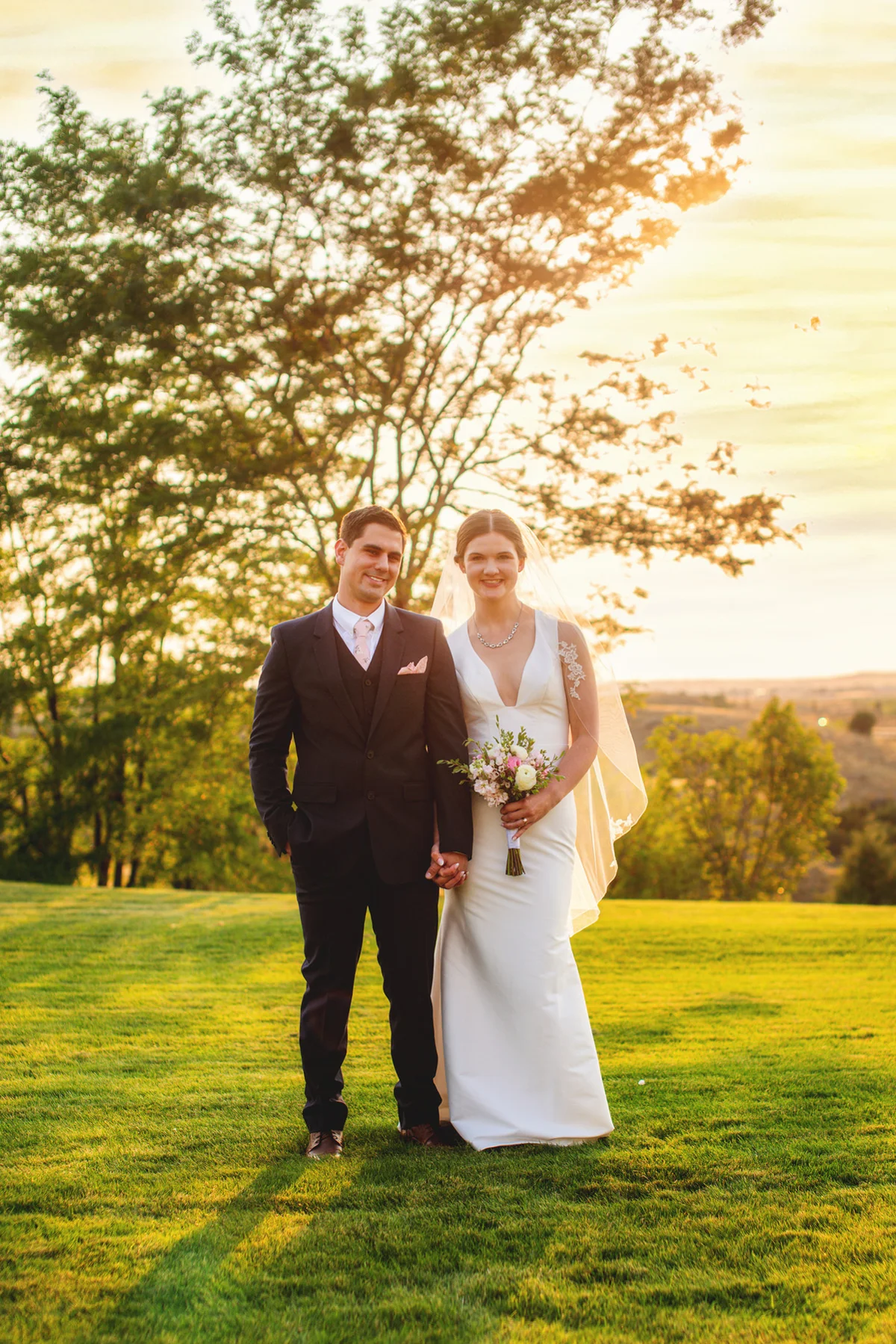 Bride and groom standing in a sunlit field