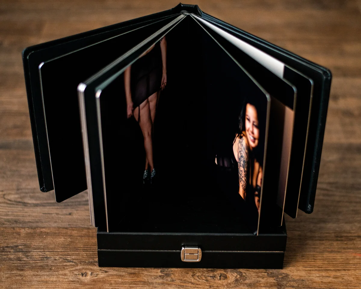 Open black leather boudoir album on a wooden table